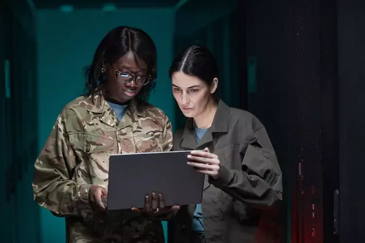 Two female military personal looking at a laptop.